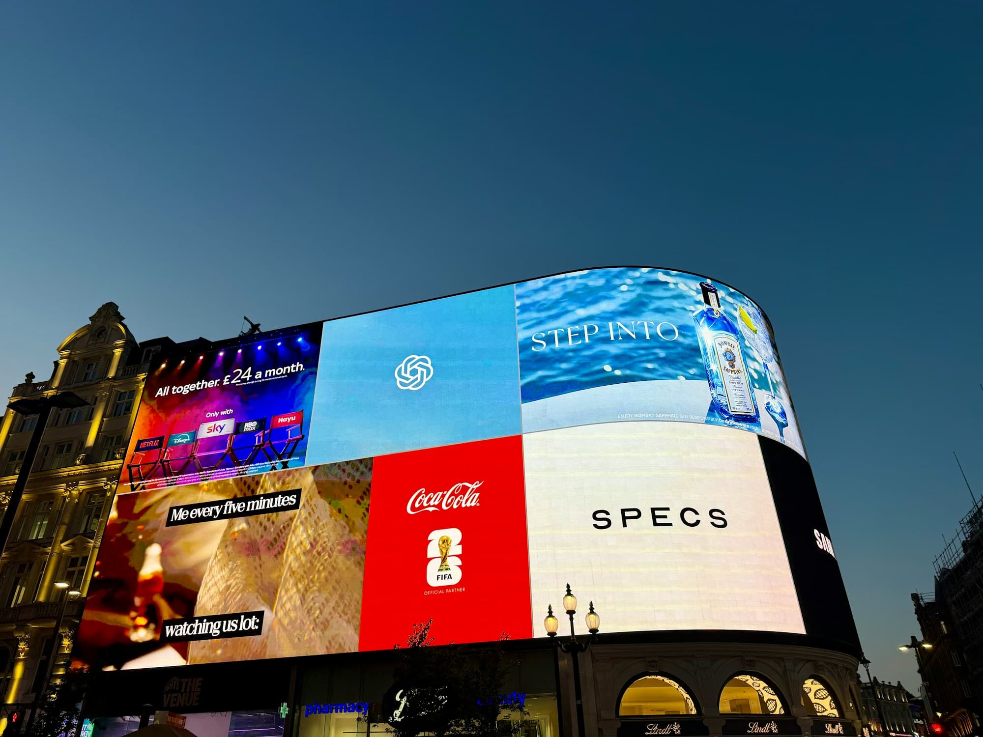 Illuminated advertising screens on a city building at dusk