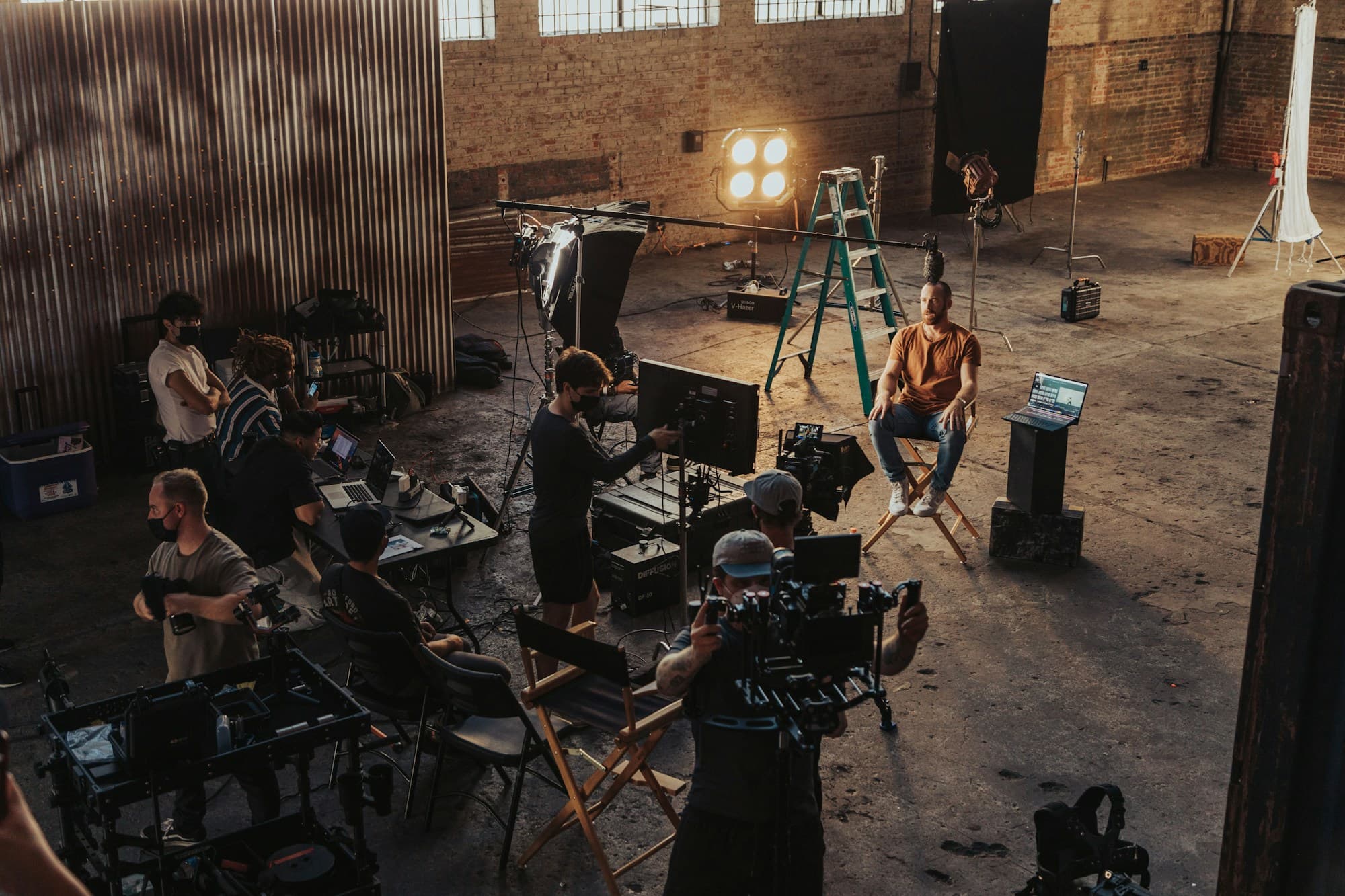 A film crew gathered around a camera rig on a warehouse set