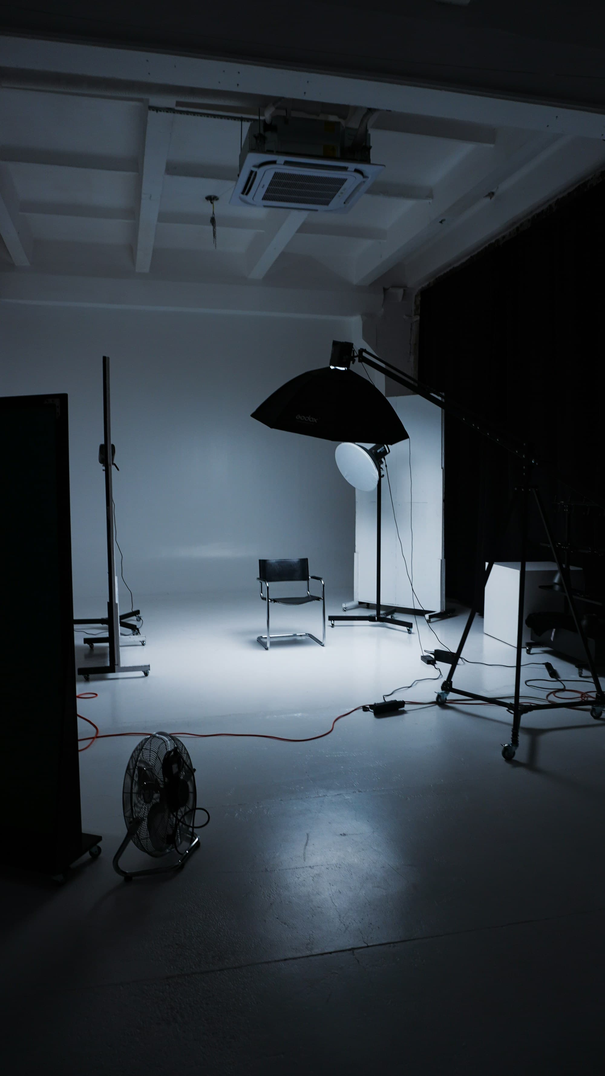An empty photography studio with lighting stands and a chair